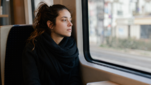 Mujer mirando por la ventana del transporte público con expresión distante, reflejando cómo la mente divaga del momento presente